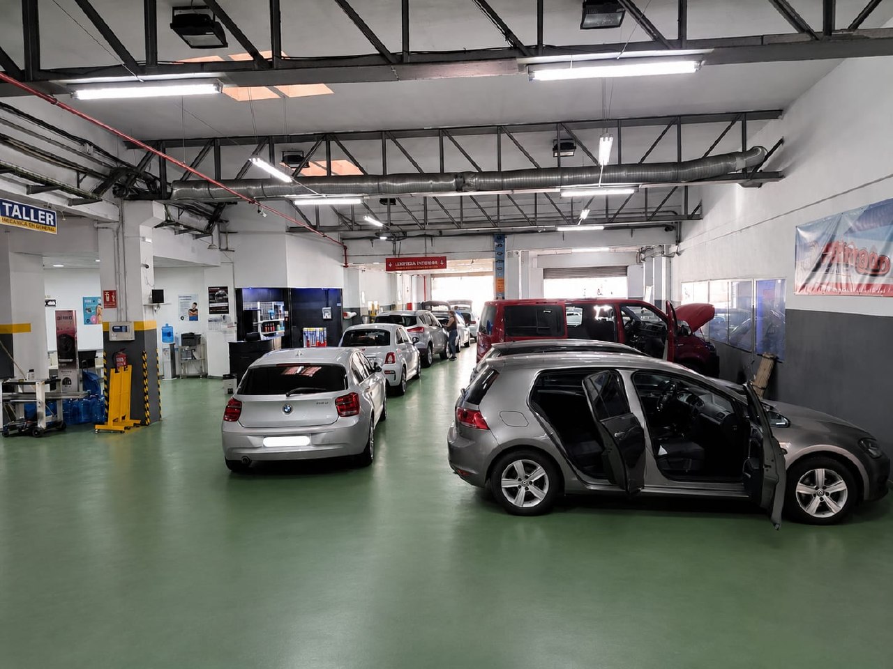 Vista general del taller con varios coches en bahías de servicio
